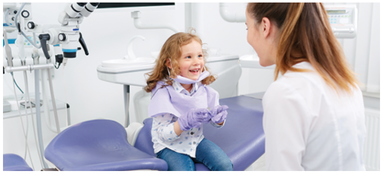 little girl smiling sitting in dental chair